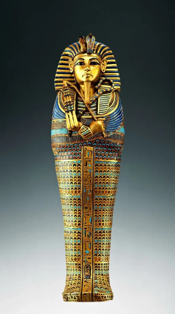 Full view of the ornate, gilded gold sarcophagus of Pharaoh Tutankhamun, inlaid with colorful lapis lazuli and turquoise glass, holding the crook and flail.